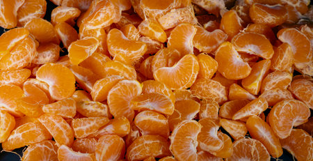 Peeled tangerines on a black background. Slices of tangerine or mandarin fruit close up.の写真素材