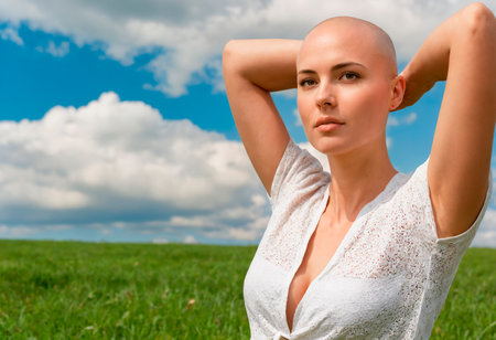 Closeup portrait of a young caucasian woman with bald head and blue sky background.の素材