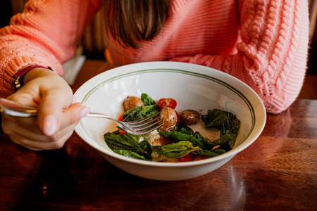 A girl sits at a table, eating from a bowl of food in a casual setting.
