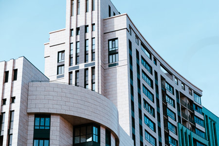A modern building showcases its unique architectural elements and design against a bright blue sky.