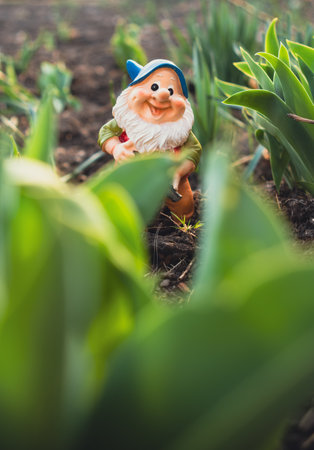 A gnome figurine stands in the center of a blossoming garden, surrounded by colorful flowers and...