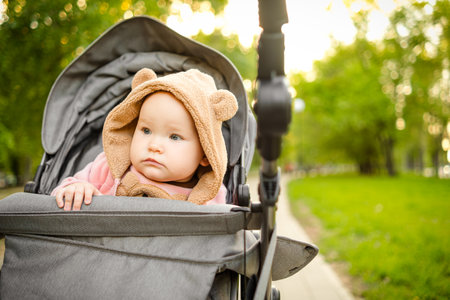 Portrait of a cute toddler girl in a stroller in the park.
