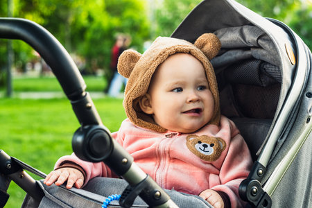 Portrait of a cute toddler girl in a stroller in the park.