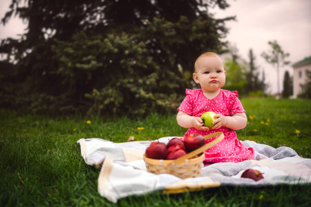 Young Girl in a Pink Dress Enjoying an Apple at the Park.