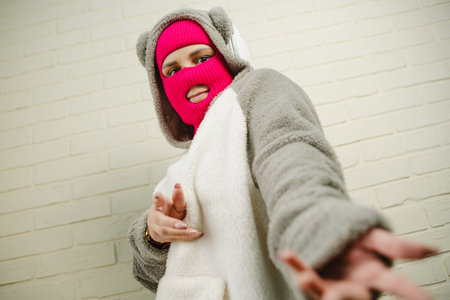 Woman in pink Balaclava Dancing Against a White Brick Wall