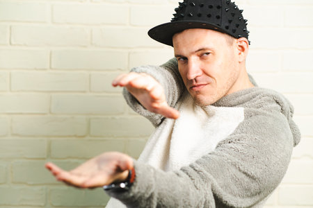 A man wearing a black cap and a gray sweater is captured in motion, dancing gracefully with fluid...