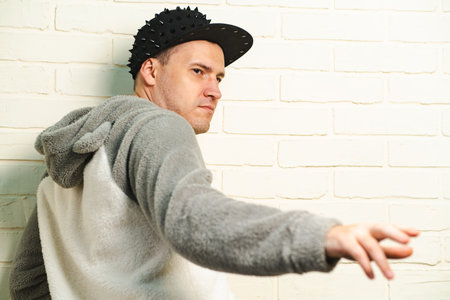 A man wearing a black cap and a gray sweater is captured in motion, dancing gracefully with fluid...