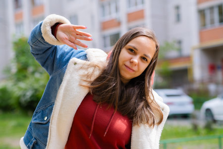 A woman is energetically dancing in front of a building. She exudes confidence and joy as she moves gracefully.の写真素材