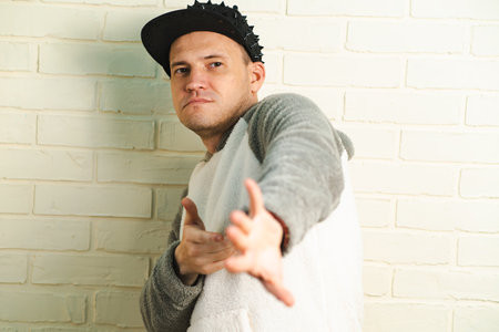 A man wearing a black cap and a gray sweater is captured in motion, dancing gracefully with fluid...