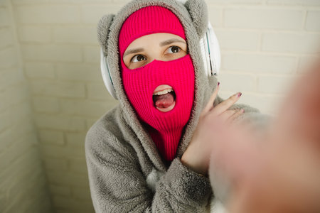 Woman in pink Balaclava Dancing Against a White Brick Wall
