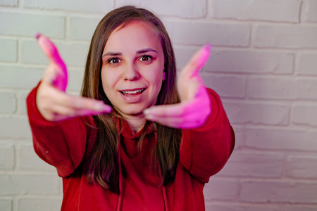 Woman Dancing Gracefully in Red Sweatshirt Against White Brick Wall at Evening.の写真素材