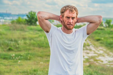 A professional sportsman in a white shirt is seen holding his hands behind his head, performing...