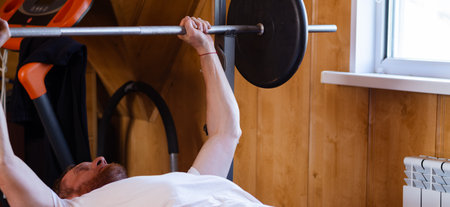 A man doing a bench press with a barbell in the gym.