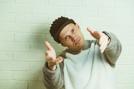 A man wearing a black cap and a gray sweater is captured in motion, dancing gracefully with fluid...