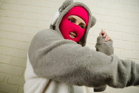 Woman in pink Balaclava Dancing Against a White Brick Wallの写真素材