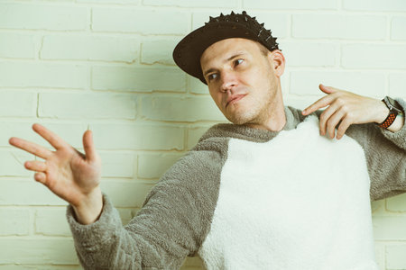 A man wearing a black cap and a gray sweater is captured in motion, dancing gracefully with fluid movements. His outfit contrasts against the background as he enjoys his danceの写真素材