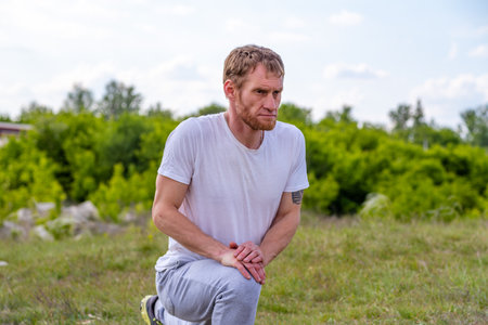 Man Stretching Leg Muscles Outdoors During Sunny Day.