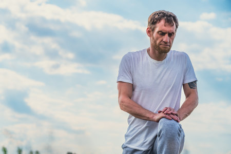 Man Stretching Leg Muscles Outdoors During Sunny Day.