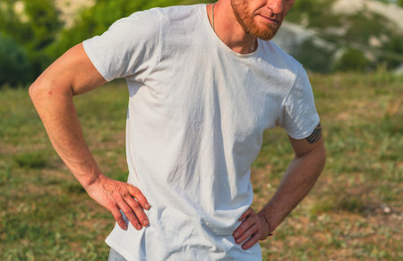 Man in White T-Shirt Warms Up After Workout in Grassy Field