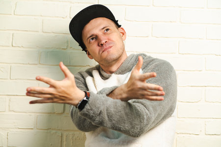 A man wearing a black cap and a gray sweater is captured in motion, dancing gracefully with fluid...