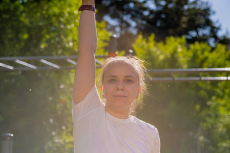 Woman performing a warm-up stretch routine in an outdoor setting. The exercise takes place on a...