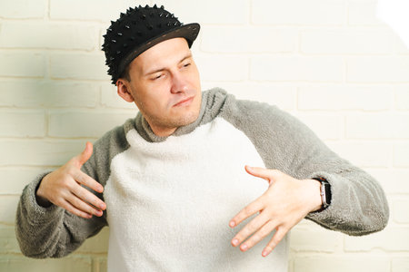 A man wearing a black cap and a gray sweater is captured in motion, dancing gracefully with fluid...