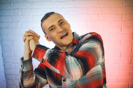 Man in Plaid Shirt Dancing in Front of a Brick Wall.の写真素材