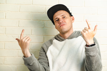A man wearing a black cap and a gray sweater is captured in motion, dancing gracefully with fluid movements. His outfit contrasts against the background as he enjoys his danceの写真素材