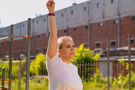 Woman performing a warm-up stretch routine in an outdoor setting. The exercise takes place on a...