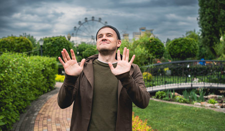 Handsome Man Dancing Enthusiastically in a Lush Green Park on a Cloudy Afternoon.の写真素材