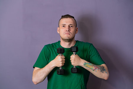 Man Lifting Green Dumbbells During Home Workout.の写真素材