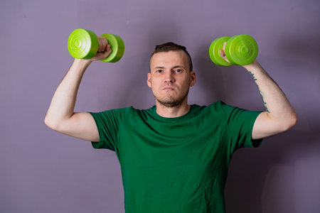 Man Lifting Green Dumbbells During Home Workout.の写真素材