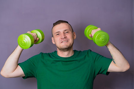 Man Lifting Green Dumbbells During Home Workout.の写真素材