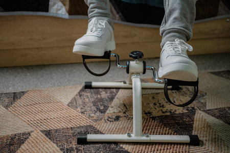 Person Using White Peddler Exercise Machine While Sitting.