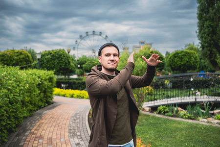 Handsome Man Dancing Enthusiastically in a Lush Green Park on a Cloudy Afternoon.の写真素材