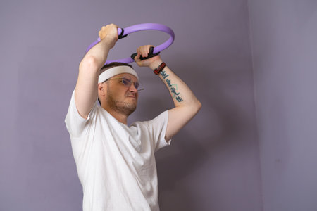 Man Holding Purple Exercise Ring in Front of Purple Wall.の写真素材