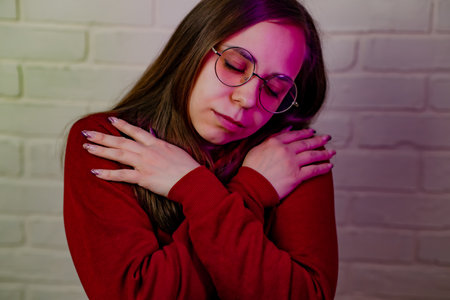 Woman Dancing Gracefully in Red Sweatshirt Against White Brick Wall at Evening.の写真素材