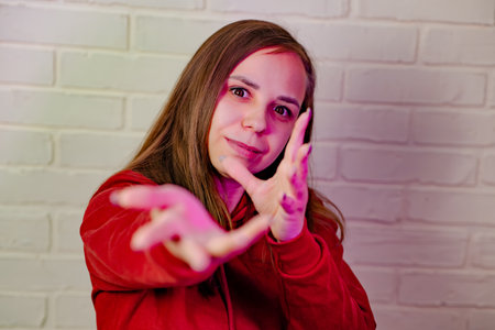 Woman Dancing Gracefully in Red Sweatshirt Against White Brick Wall at Evening.の写真素材