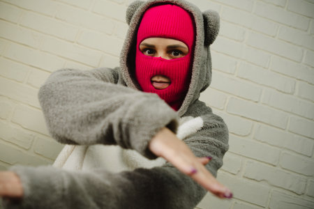 Woman in pink Balaclava Dancing Against a White Brick Wallの写真素材