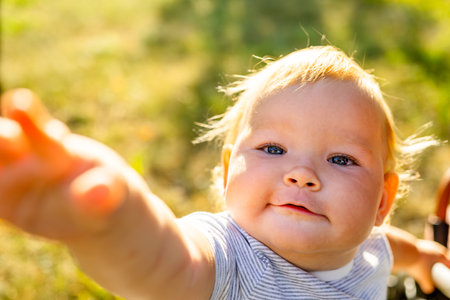 Toddler Enjoys Sunny Day Outdoors Among Green Grass and Yellow Dandelions in Spring.の写真素材