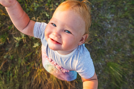 Happy Baby Enjoying Sunshine While Playing Outdoors in a Green Field.の写真素材