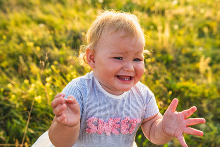 Happy Baby Enjoying Sunshine While Playing Outdoors in a Green Field.の写真素材