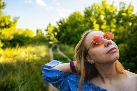 A Young Woman Enjoys a Sunlit Nature Path During a Clear Day in Summer.