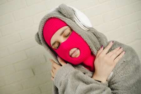 Woman in pink Balaclava Dancing Against a White Brick Wallの写真素材