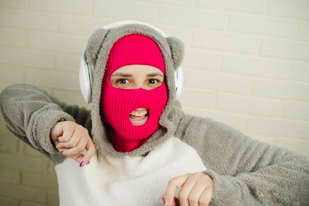 Woman in pink Balaclava Dancing Against a White Brick Wallの写真素材