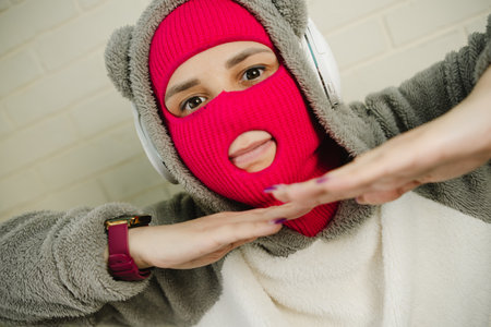 Woman in pink Balaclava Dancing Against a White Brick Wall
