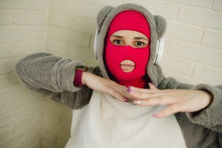 Woman in pink Balaclava Dancing Against a White Brick Wall
