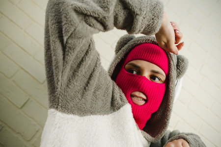 Woman in pink Balaclava Dancing Against a White Brick Wall