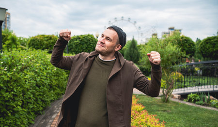 Handsome Man Dancing Enthusiastically in a Lush Green Park on a Cloudy Afternoon.の写真素材