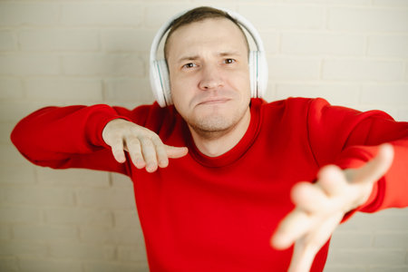 Man In Red Sweatshirt Moving While Listening To Music With Headphones.の写真素材
